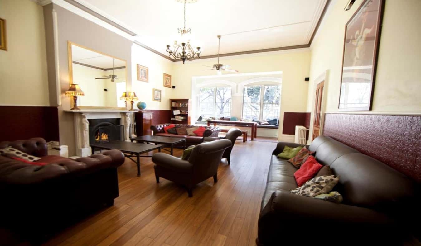 Cozy, light-filled common area with lots of couches, tables, and a fireplace at The Nunnery hostel in Melbourne, Australia.