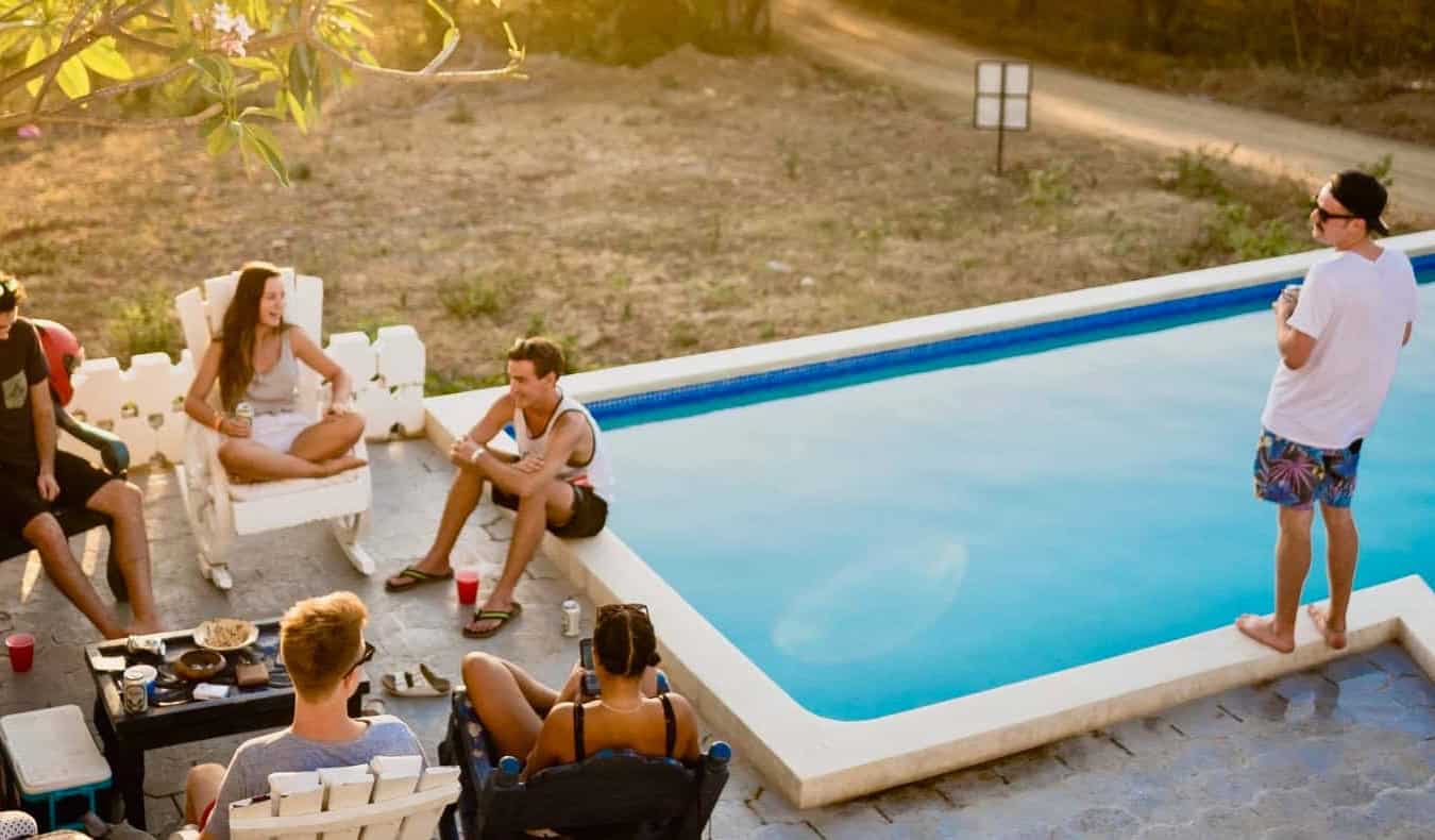 A group of travelers hanging out by the pool at a fun and social hostel