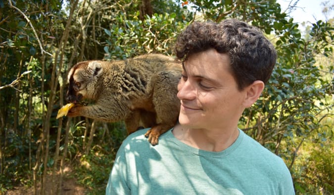 Nomadic Matt poseert met een lemuur op het Lemureneiland in Madagaskar